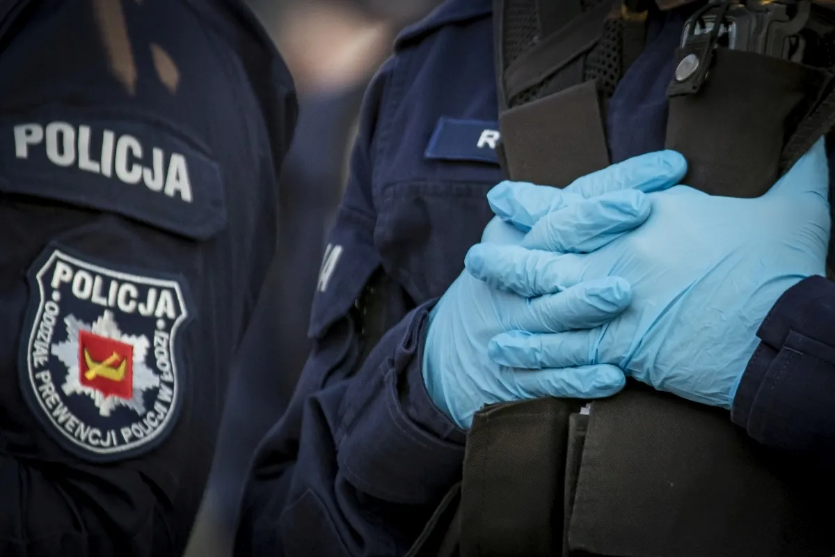 Blue medical gloves clasped over a police uniform